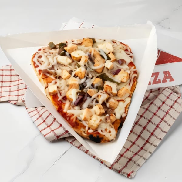 A small, heart-shaped pizza with chicken, onions, and green peppers in a white box.